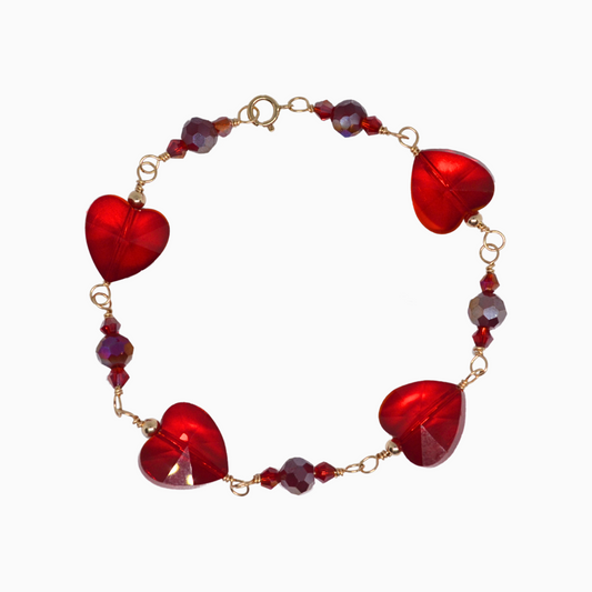 A close-up image of a handcrafted January Garnet-inspired bracelet, featuring deep red glass crystals in 3mm bicone and 6mm round shapes. A stunning 14mm crystal heart serves as the focal point, reflecting rich garnet hues. The bracelet is elegantly designed to capture the warmth and passion of the January birthstone.